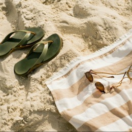 flip flops and sunglasses on a towel and a sandy beach