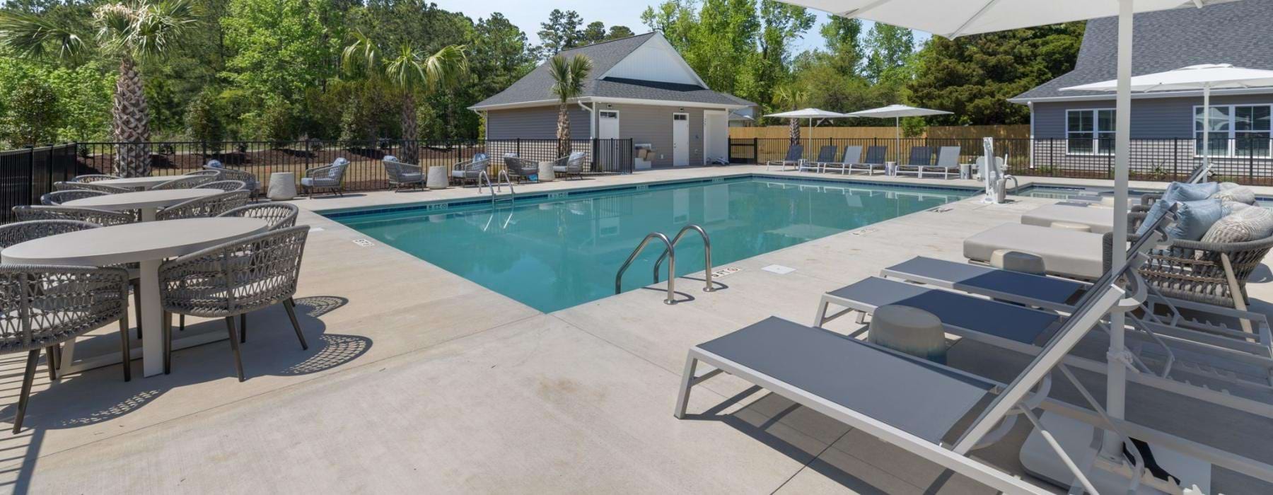 a swimming pool with white umbrellas and poolside lounging